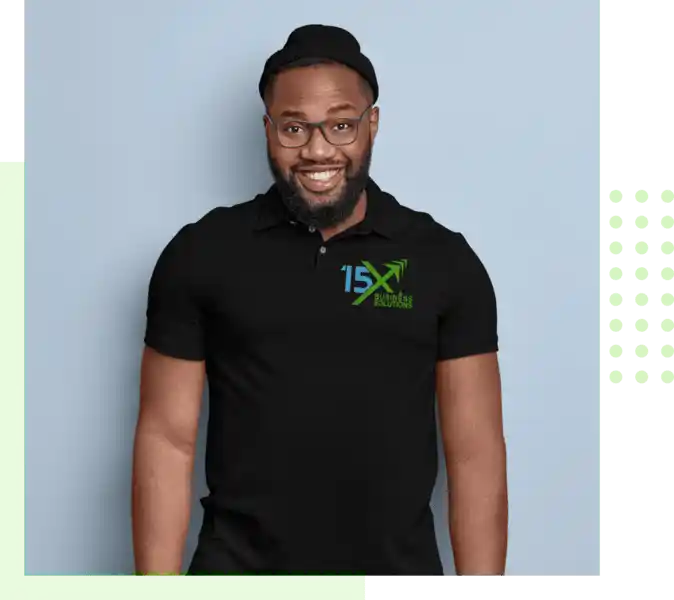 15X Business Solutions team member wearing a black branded polo shirt, glasses, and a black cap, smiling against a light background.