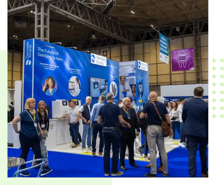 Dental industry trade show featuring a Dentsply Sirona exhibition booth with attendees networking and exploring dental technology solutions.
