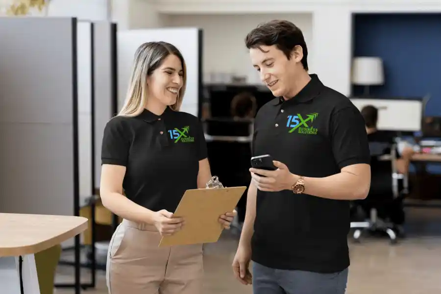 15X Business Solutions team members reviewing information together on a clipboard and smartphone in a modern office.
