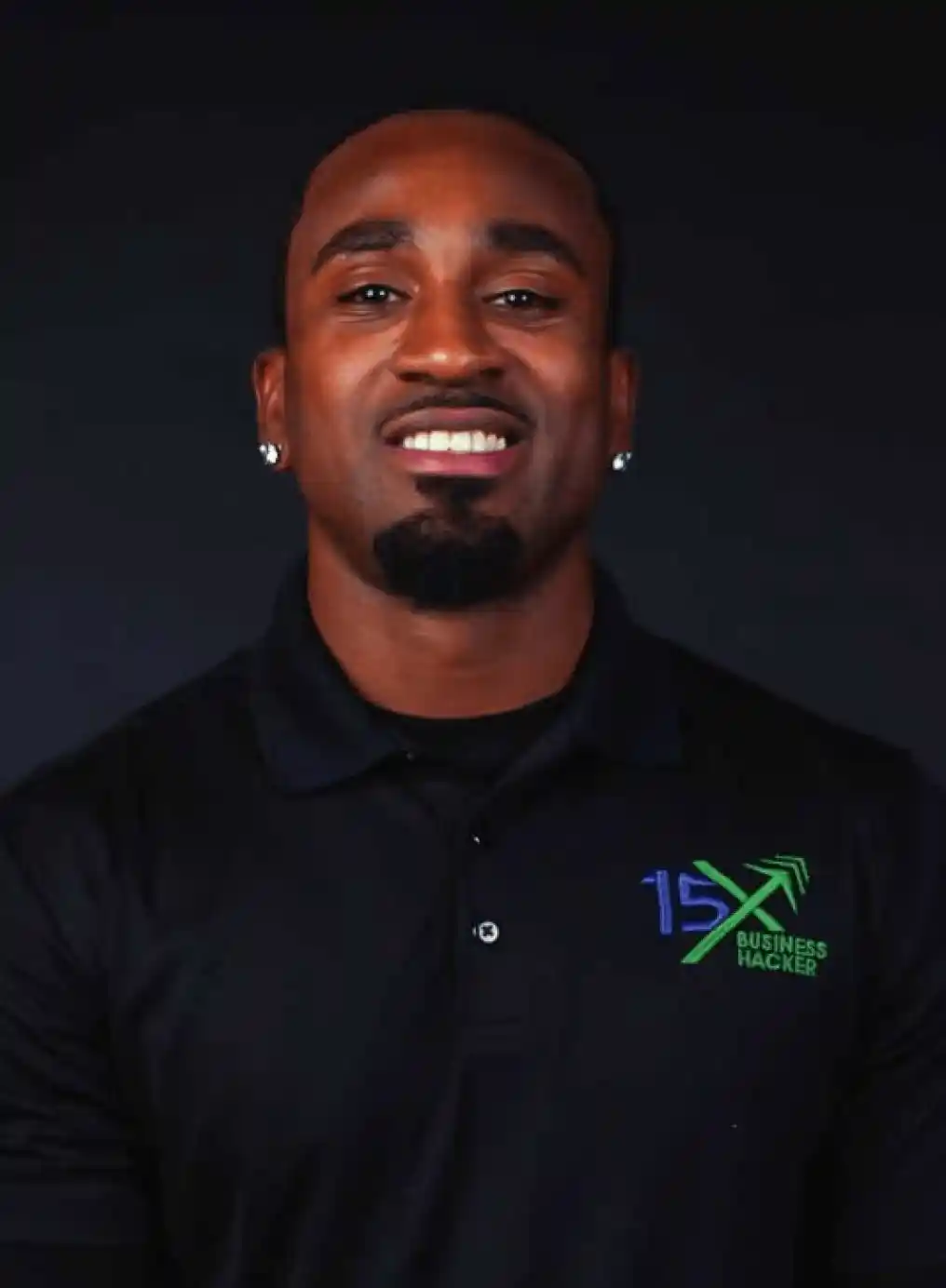 15X Business Hacker representative wearing a black branded polo shirt, smiling against a dark background.