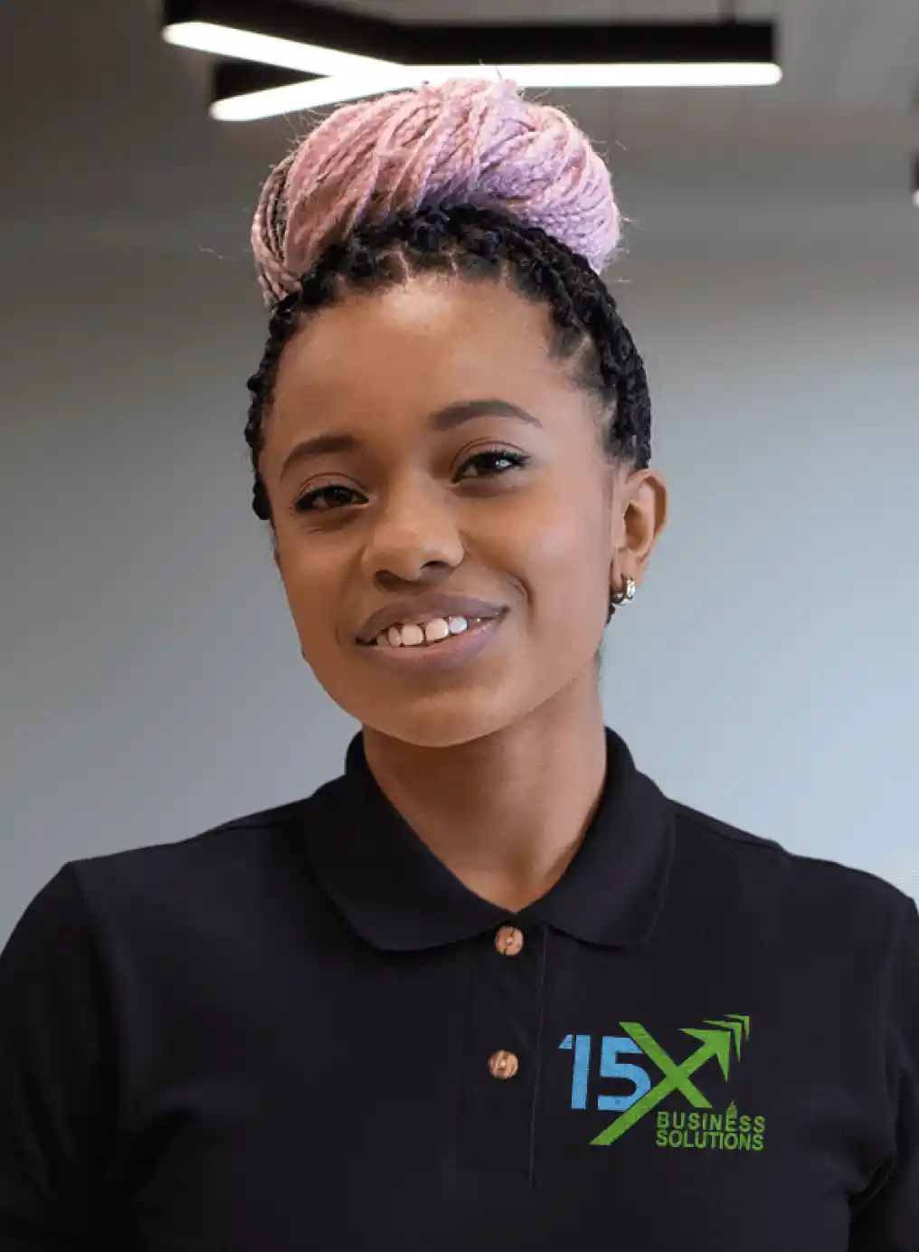 15X Business Solutions team member wearing a black branded polo shirt, smiling in a modern office setting.