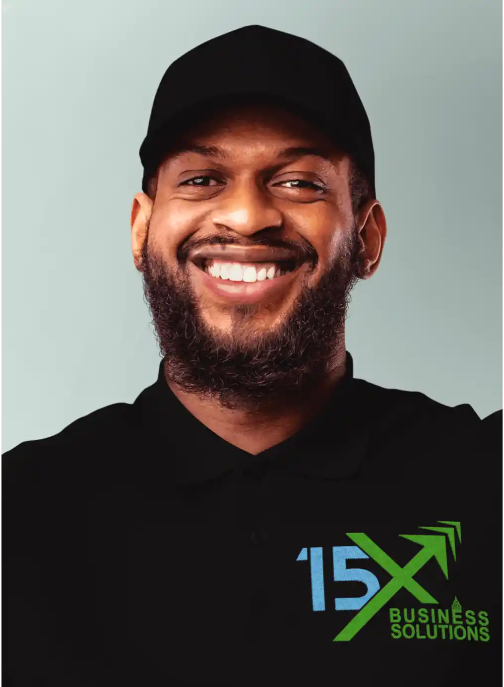 15X Business Solutions team member wearing a black branded polo shirt and black cap, smiling against a light background.